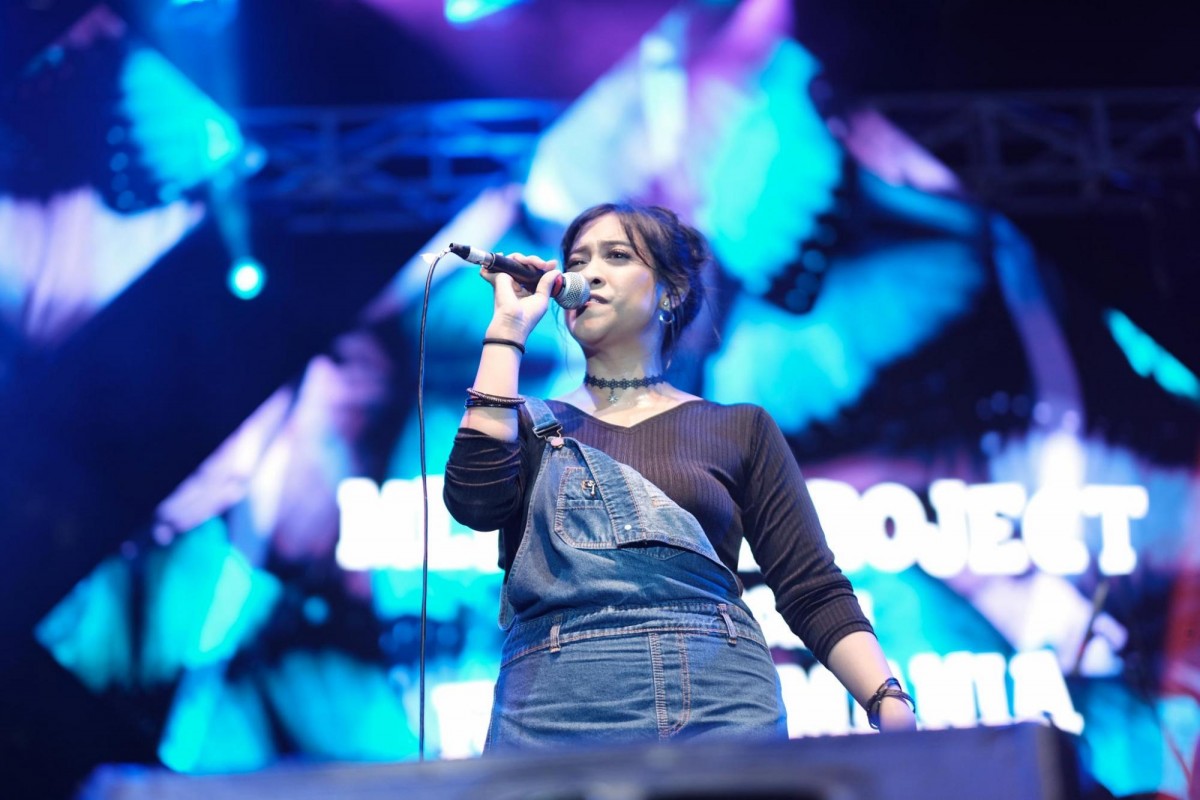 Puspa dengan longsleeve hitam dan overall denim bernyanyi di MLDSPOT Stage The 90s Festival 2019